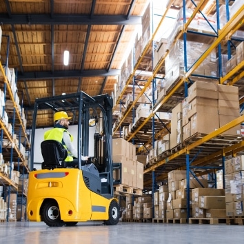 Man in warehouse driving forklift