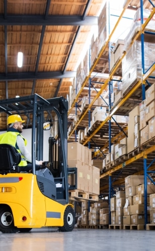 Man in warehouse driving forklift